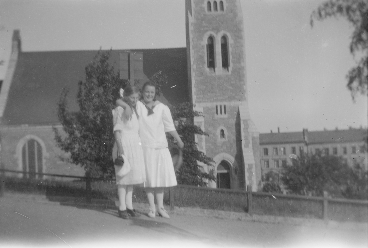 To unge damer fremfor en kirke i en by