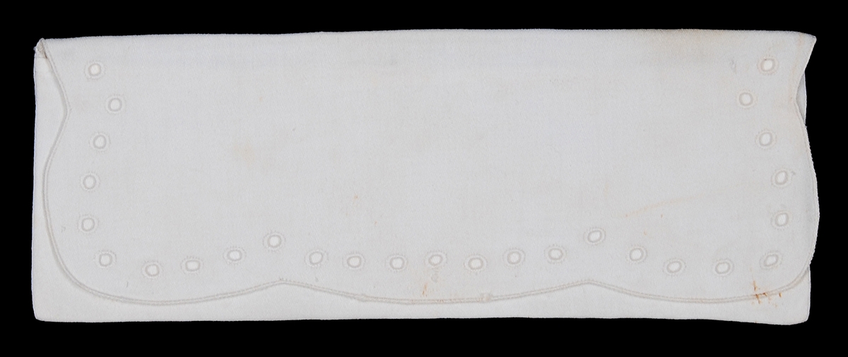 Av vit bomullsväv s.k. angolaväv, kuvertmodell med övervikt lock, en rad kantsydda hål runt locket.