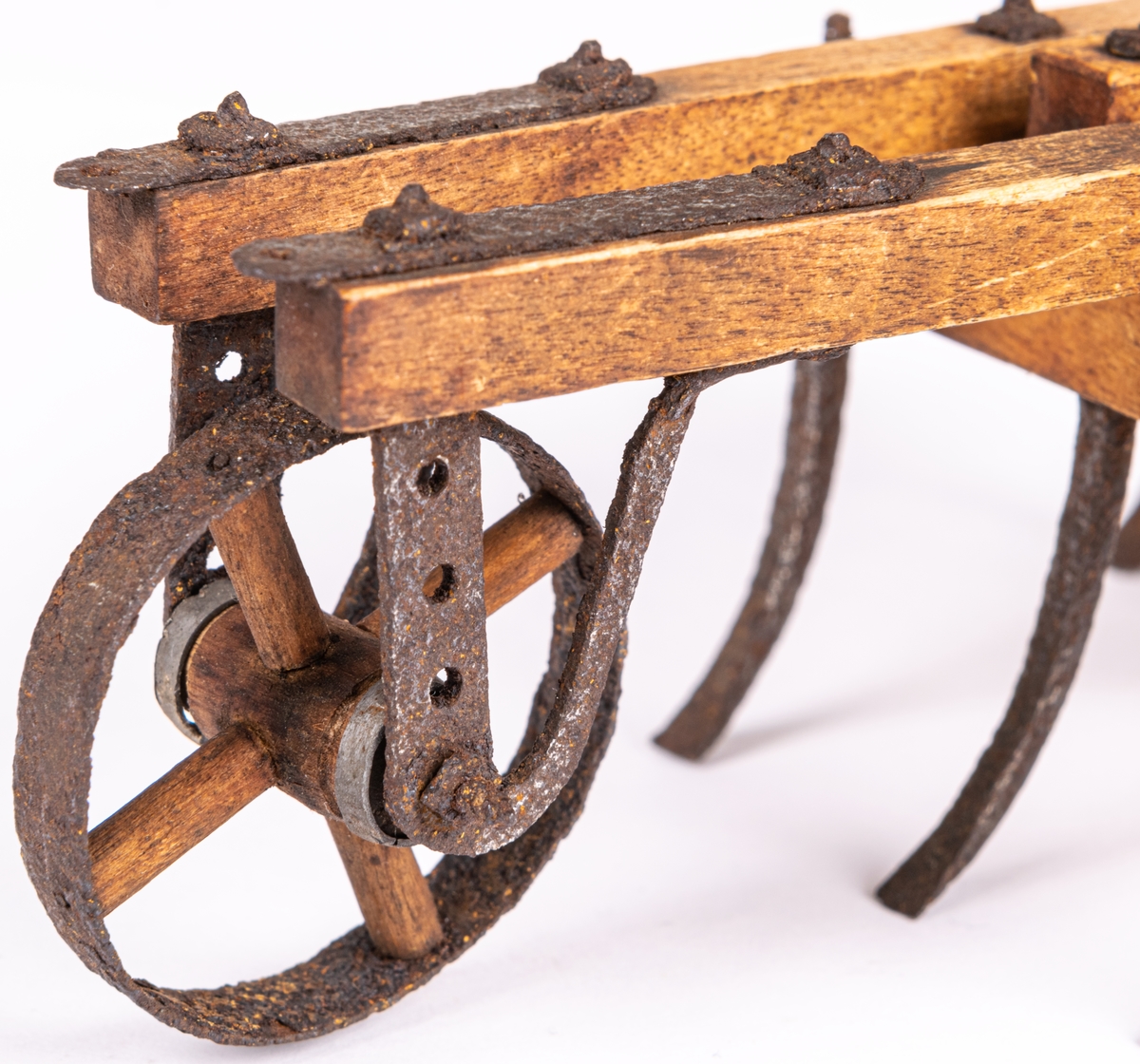 Modell till exstirpator, kallad klösharv, med hjul, åkerbruksredskap. Fyrsidig ram av träbalkar, sture av trä, två framåtriktade åsar, 7 stycken harvjärn i balkramen. Modellens längd 23,5.