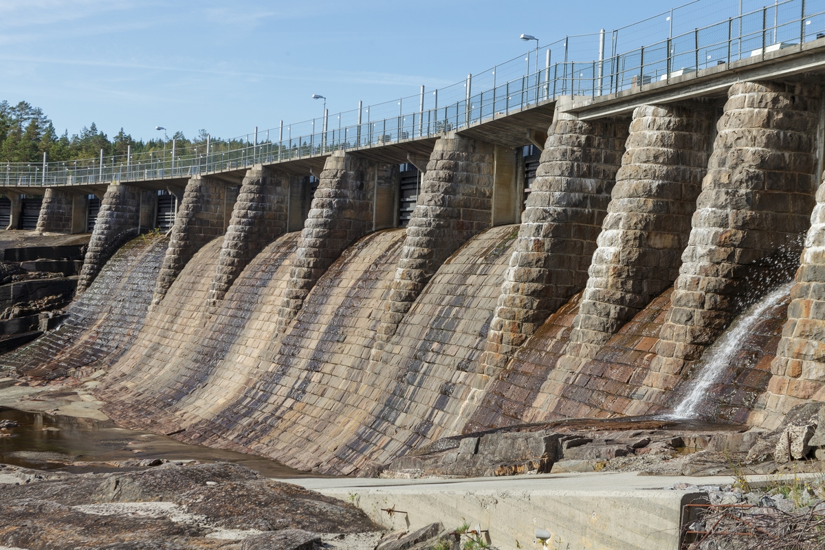 Haugsjå dam. Haugsjådammen nedstrøms. Dammen er ein 180 meter lang massivdam kledd med naturstein, granitt frå Fjære, Aust-Agder, og har ein utprega hoppbakkeform i flomløpet. Sett mot V.
