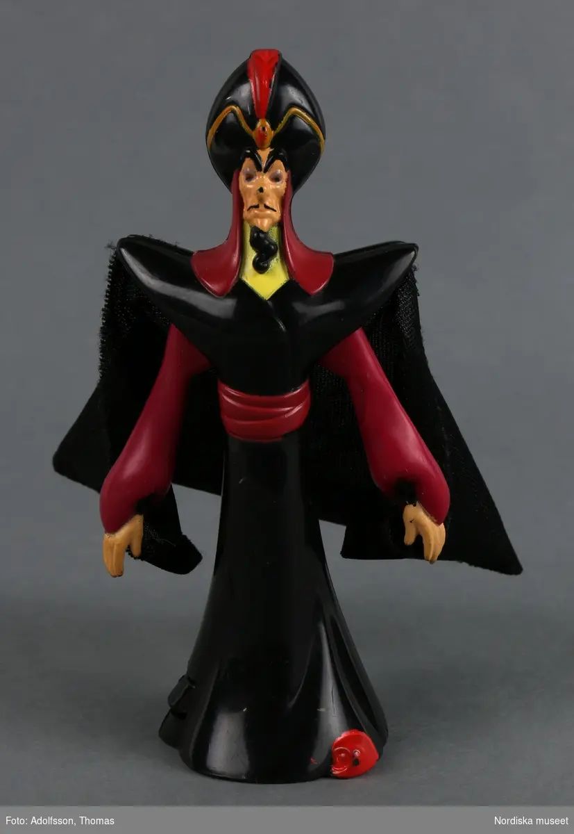 Mekanisk leksak som föreställer den maktlystne storvisiren Jafar. Han är klädd i en svart och vinröd kaftan, turban och slängkappa. Han har skägg och svarta ögonbryn. Armarna är rörliga. Om man trycker på mekanismen fälls armarna ut.
