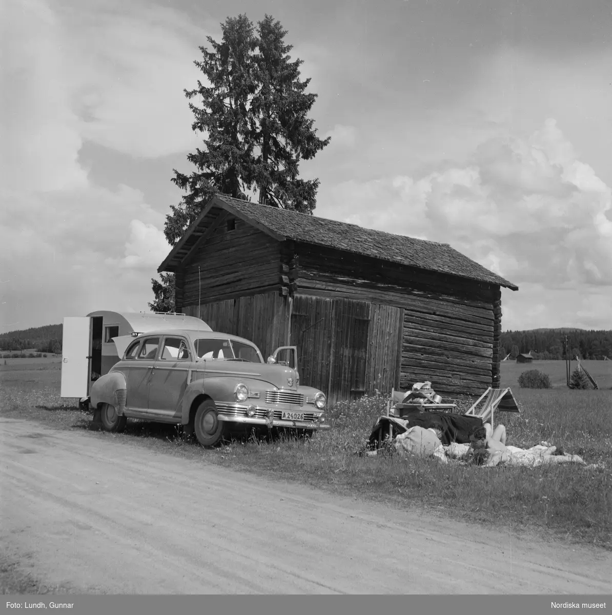 Motiv: (ingen anteckning) ;
Porträtt av en man författaren Frans G Bengtsson, en gärsgård, två kvinnor och två män ligger på marken och spelar schack vid en parkerad bil med husvagn, en kvinna står vid dörren till en husvagn, porträtt av en flicka som håller blommor.