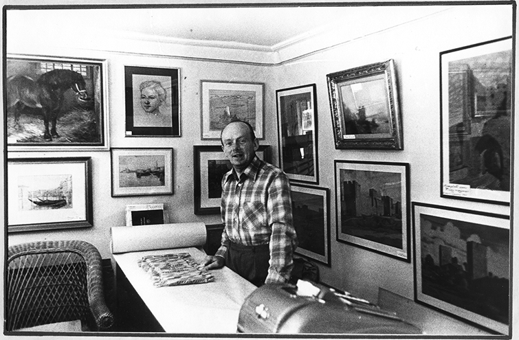 Konsthandlare och tavelramare Gunnar Edén i sin butik på Brahegatan 71. Han står lutad mot sin disk, bakom honom hänger ett flertal tavlor på väggarna.