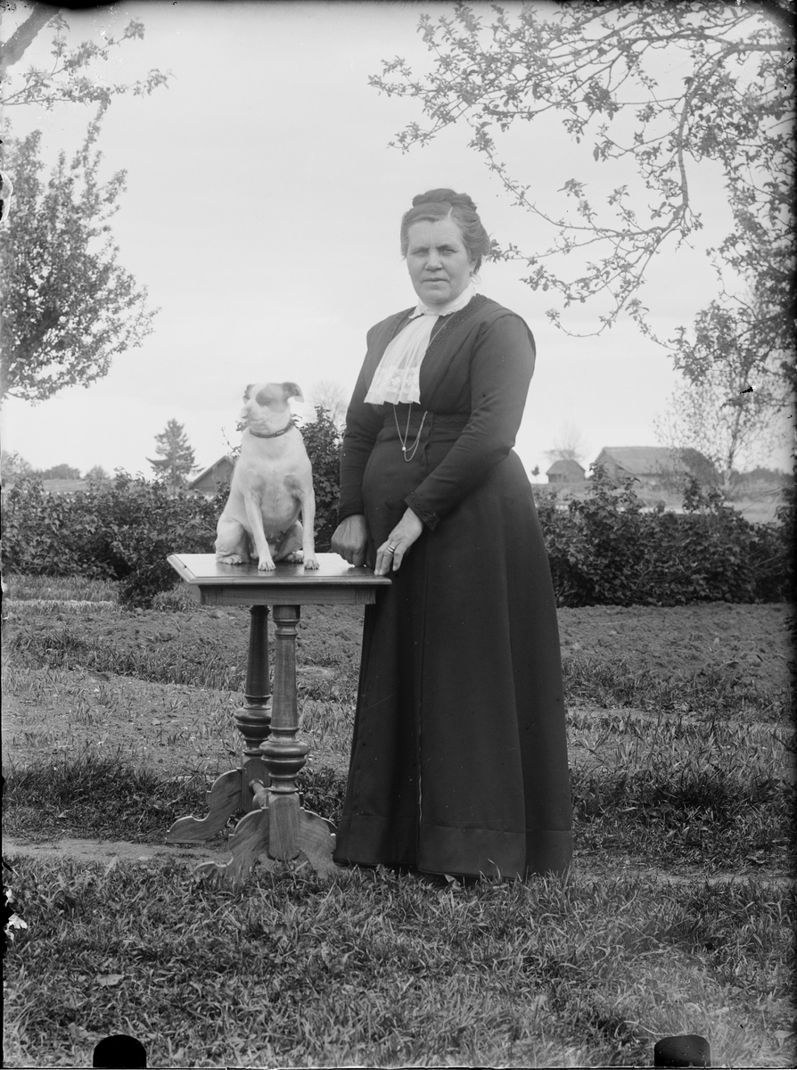 Kvinna med hund i trädgård, Alunda, Uppland