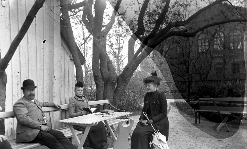Tre personer sittande i Öjermarks trädgård, Västerås.