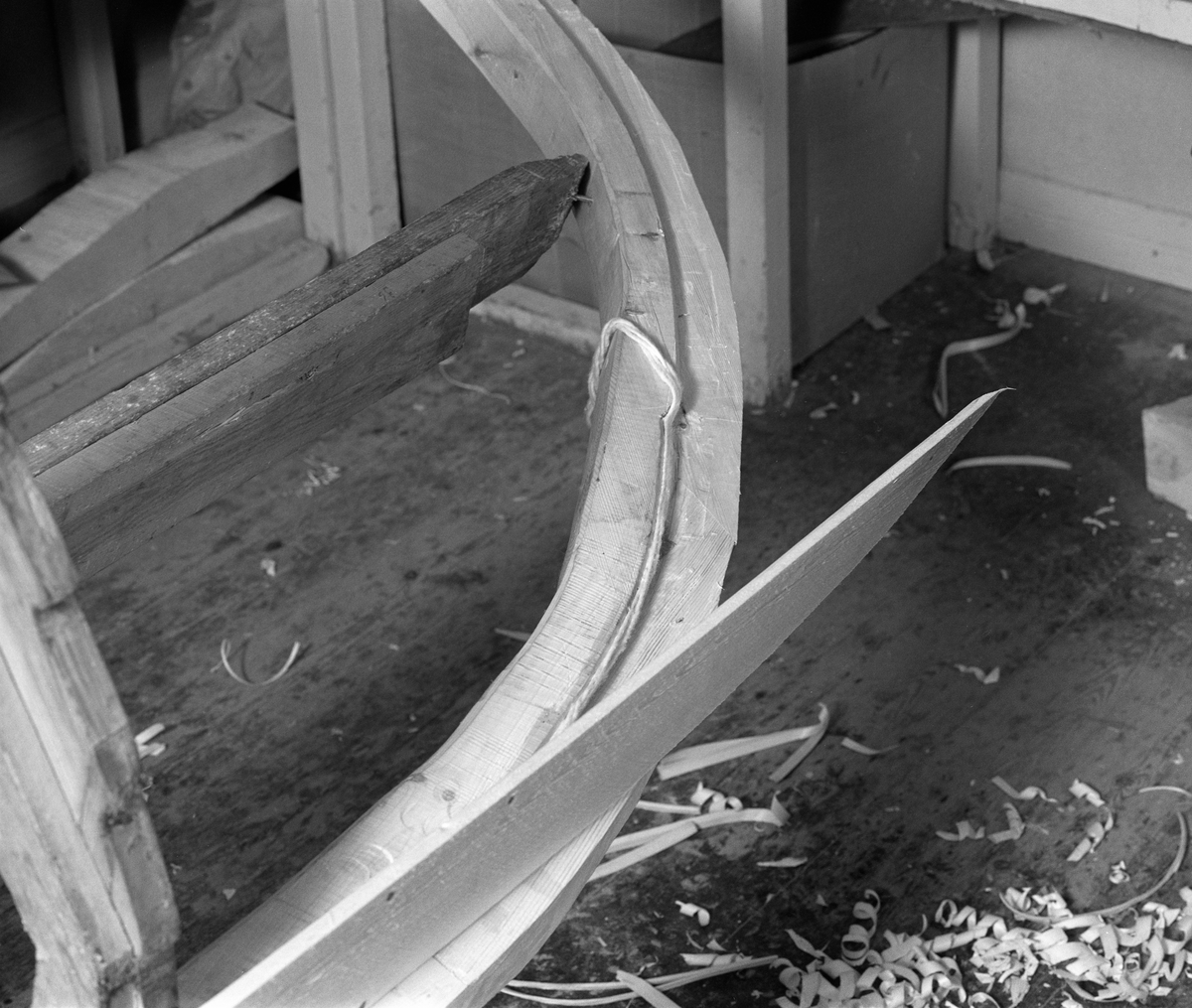 Bygging av fløterbåt i Glomma fellesfløtingsforenings verksted Breidablikk ved kommunesenteret Flisa i Åsnes i november 1984. Båttypen ble for øvrig kalt «Flisabåt», men denne modellen var egentlig utviklet av John Dybendal (1904-1985) omkring 1930. Målet var å kunne levere en robåt som passet i elva Flisa. Dybendal bygde sjøl slike båter fram til 1949. Glomma fellesfløtingsforening hadde vært en viktig kunde hos Dybendal, og da han gav seg som båtbygger ble virksomheten flyttet til denne virksomhetens verksted for Solør-regionen, hvor båtbygging ble vinteraktivitet for et par av karene som hadde vassdraget som arbeidsplass sommerstid. Det var maler til alle båtdeler, og skroget ble bygd på tverrmaler som ble festet til kjølen. Dette var hjelpemidler som gjorde det mulig for fløtere med reletivt liten håndverkserfaring å bygge denne båttrypen og oppnå den standardiserte formen som fløterkameratene var vant med. De fleste flisabåtene fikk jernspanter, for det var krevende å finne de krokvokste emnene som gav de beste spantene. Ettersom Norsk Skogbruksmuseum dokumenterte båtbygginga ville karene likevel bruke trespanter. Dette fotografiet viser hvordan Lars Bernhard Olastuen (1927-1998) la bomullstråd som skulle fungere som pakning i sammenfløyninga mellom kjølen og førstebordet. Flisabåtene ble, som dette bildet viser, bygd løst. Kjølen var ikke fastspent i verkstedet, og den utferdige båten kunne dermed vippes fra side til side slik det passet under ulike faser i arbeidet.

Båten som var under bygging da dette fotografiet ble tatt ble seinere overlatt til Norsk Skogbruksmuseum, der den fikk nummer SJF.07823 i gjenstandssamlinga. Den er 518 centimeter lang og 153 centimeter bred. Odd Jensen har seinere lagd oppmålingstegninger, som også finnes i museets arkiv.