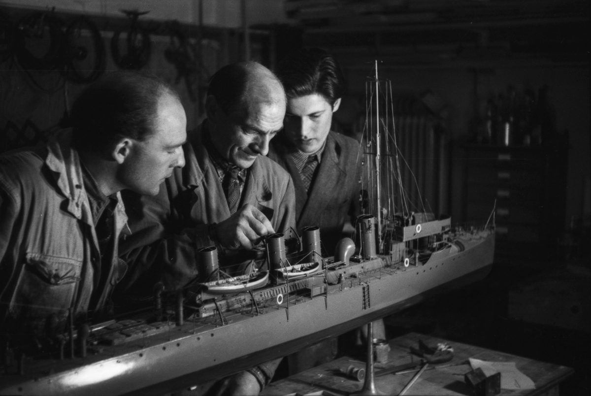 Modellbyggarna (fr. v.) Oscar Blixth, Oscar Wahlström och Sture Sandmark reparerar en modell av jagaren WALE i Sjöhistoriska museets modellverkstad.