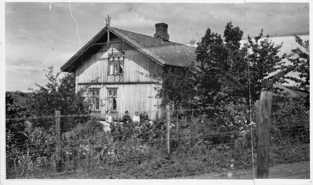 Fem personer står ved solveggen ved et hus med hage rundt. Livørsbygning