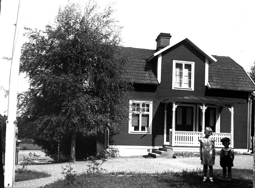 Två barn framför ett hus.