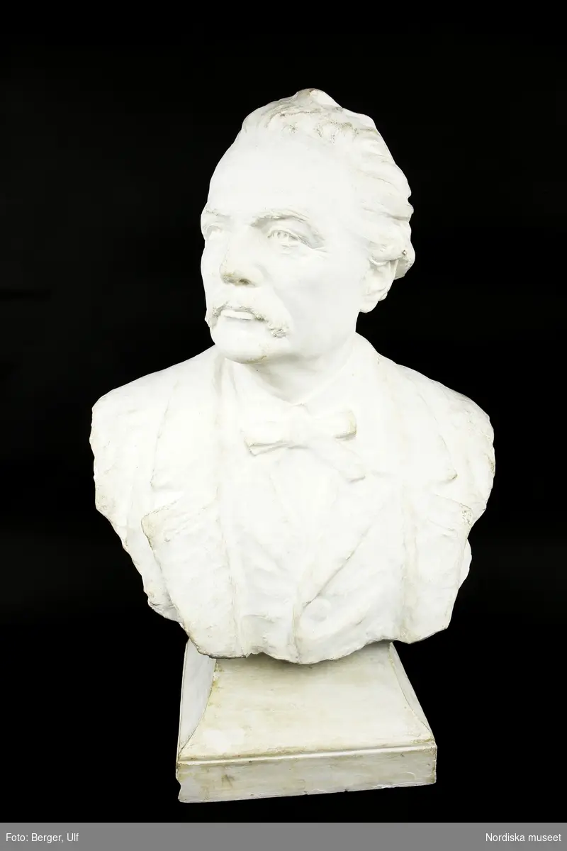Huvudliggaren:
"a-c, Byst, 3, st, skulptur, gips; porträtt av Artur Hazelius; klädd i kavaj, väst, kravatt; huvudet vänt åt höger; skador se bilaga. Br 46 cm.
[Tillv.] J. A. Wetterlund (1858-1927], 1903; funnen omärkt på vinden.
G. 15/9 1981 [av] Okänd."