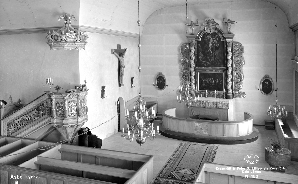 Interiör av Åsbo kyrka. Den vackra predikstolen i barockstil är skänkt till kyrkan av Gabriel Ribbing och hans hustru Beata Sparre. Hon skänkte också en kopia av hovmålaren Georg Schröders nattvardsbild i Drottningholms slottskyrka. Målningen hänger som en av kyrkans två altartavlor vid den dominerande altaruppsatsen, även den i barockstil. Den andra altartavlan är ett ateljéarbete från 1600-talet som skildrar Jesus nedtagande från korset. Dopfunten från 1200-talet är kyrkans äldsta inventarium.