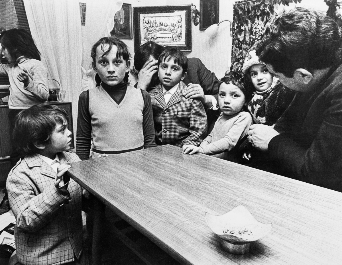Ett antal romer, de flesta barn, avfotograferade i ett vardagsrum. Några barn bär kavaj.