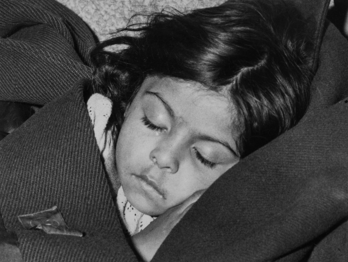 En romsk flicka sover lugnt i sin pappas kavaj. Bilden är tagen våren 1954.