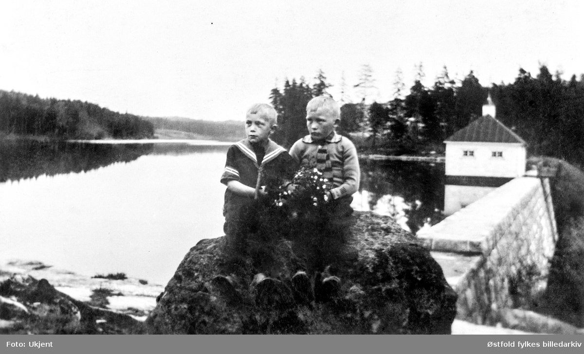 Vannbassenget i Borredalen i Rolvsøy, 1915-20? I forgrunnen brødrene Gundersen, sønner av Kristine og Martin Gundersen i Bjørndalen. Blomsterbukett med hvitveis.