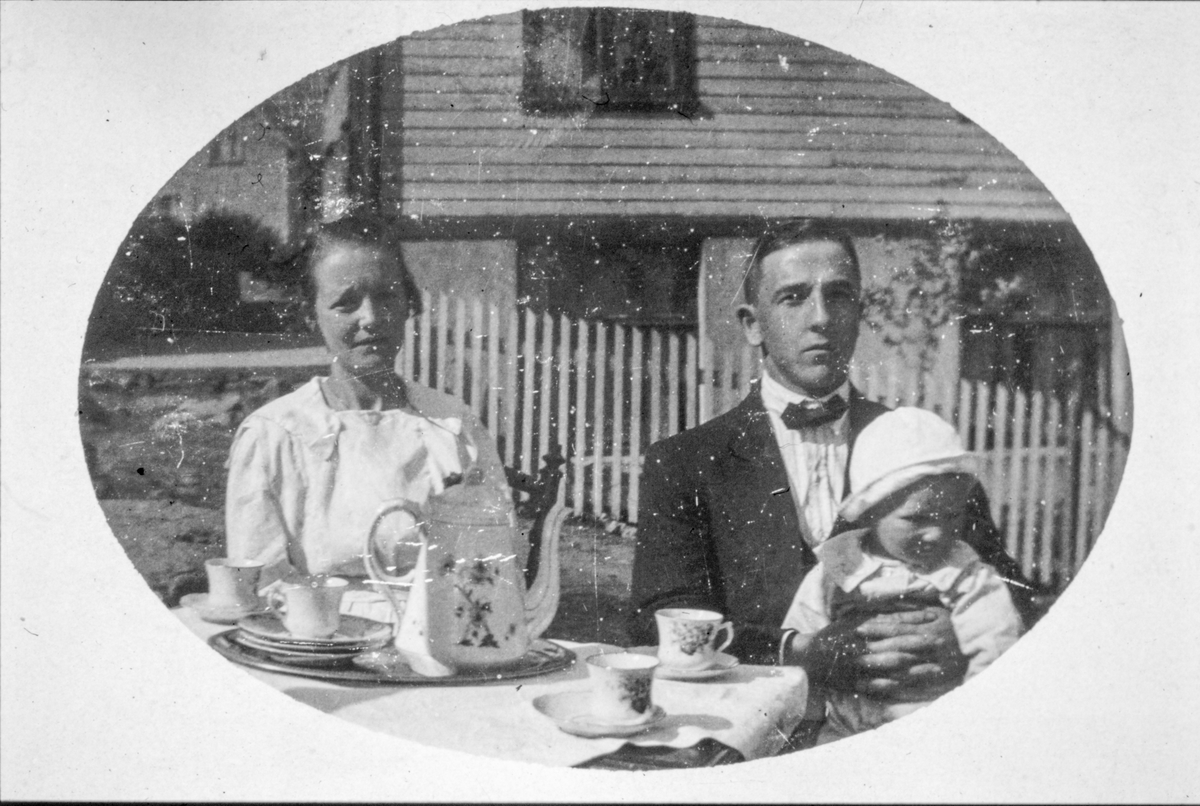 Foreldre og barn ved kaffibordet i hagen.