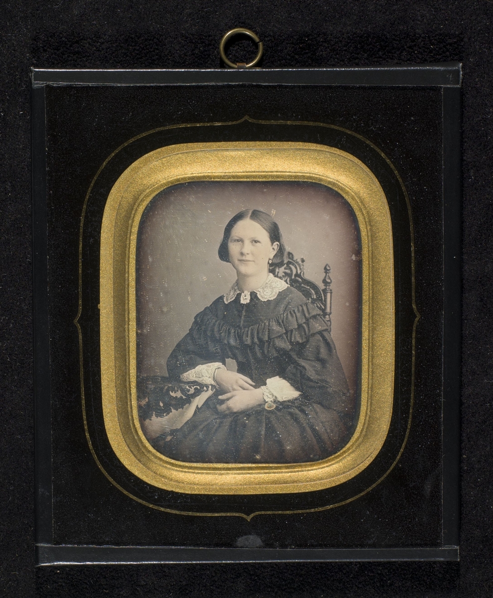 Daguerreotypi av ung pike i mørk kjole med hvite blonder, sittende ved et bord. Den avbildede skal være Mette Johanne Offersen.