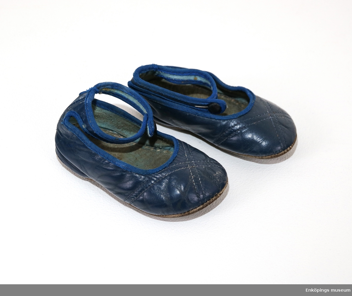Blå barnsko med slejf, sandalmodell. Skorna är från 1950-talet.