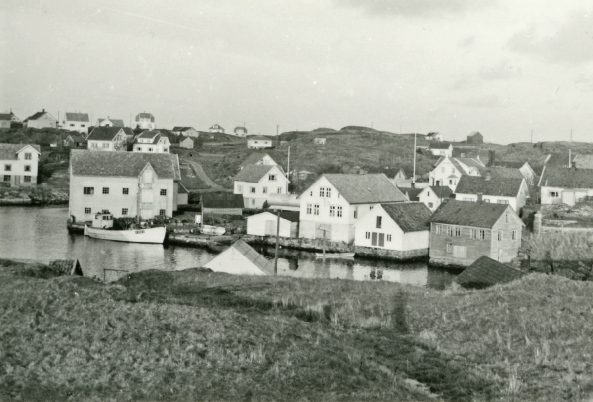 Parti fra Sevland før forretningen til Johannes Johannessen ble bygget. Skip ved kai. Fjellknaus i forgrunn. Bebyggelse i bakgrunnen.