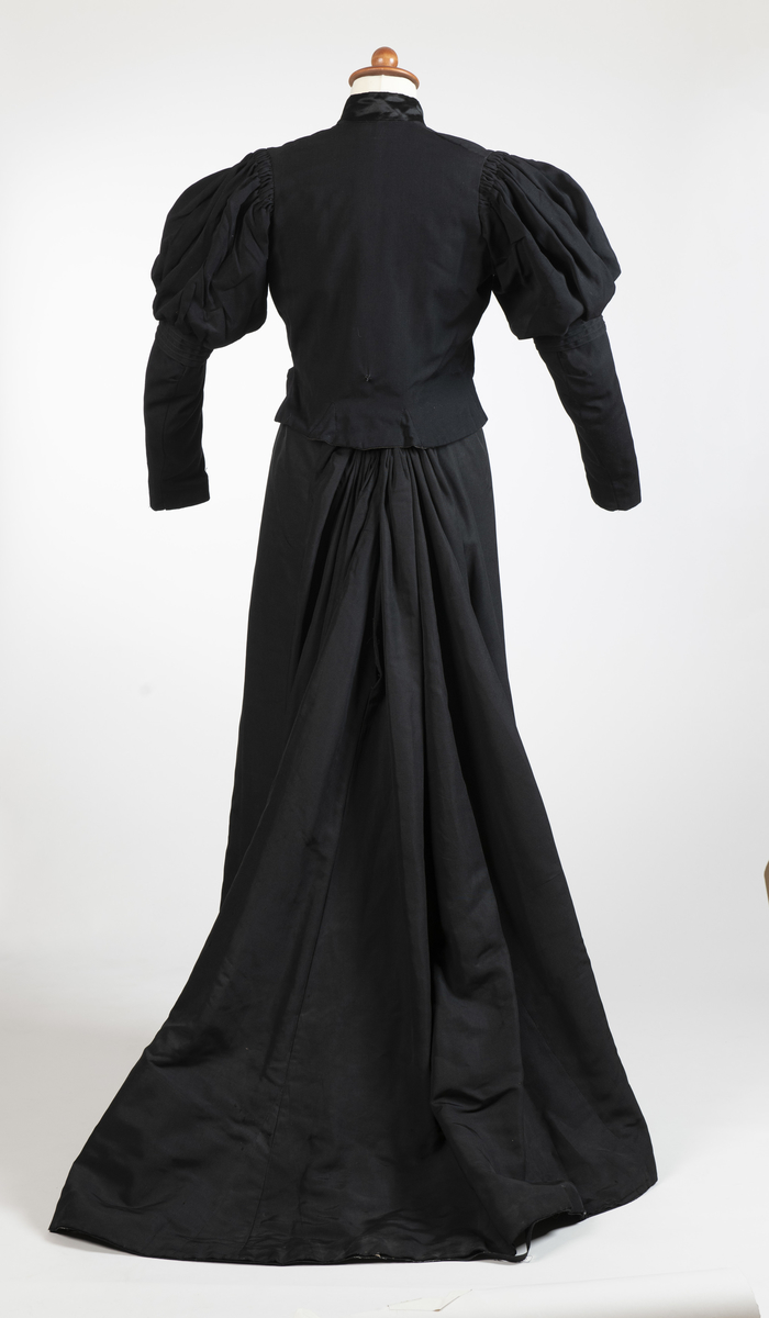 Kjole i to deler, bestående av skjørt og kjoleliv av tynt, sort ullstoff. 