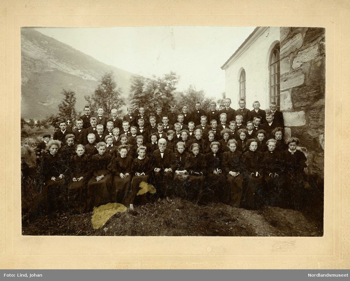 Konfirmantene utenfor Steigen kirke 1906. 64 ungdommer og klokkeren Kristian Kristensen. Kirkegården i bakgrunnen.