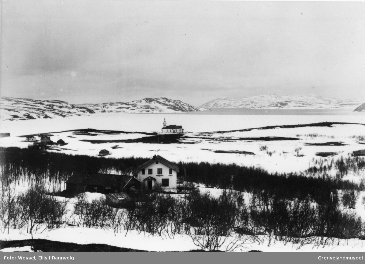 Utsikt over Bøkfjorden 26. mai 1899, fjorden er ennå islagt og det er fortsatt snø på bakken. Doktorgården Solheim i forgrunnen og Kirkenes kirke i bakgrunnen.