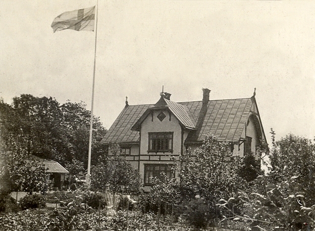 Ett bostadshus i en lummig trädgård.

Jfr Alb12-135 och 138.