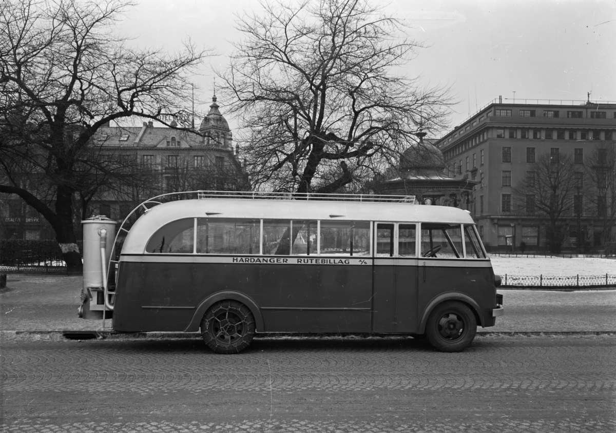 Rutebil fra Hardanger Rutebillag a/s. Musikkpaviljongen, byparken og Hotel Norge i bakgrunnen.
