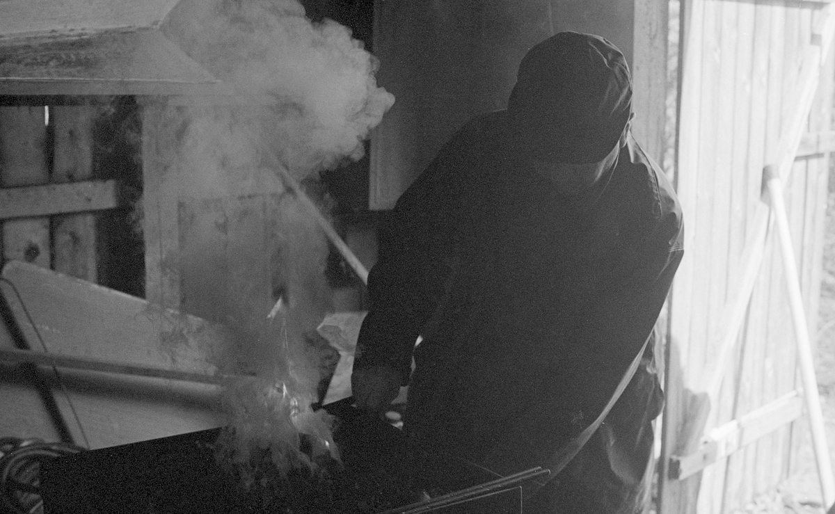 Harald Øren (1921-2000) fyrer opp i smia ved fløtingsstenteret Sørlistøa ved Osensjøen i Åmot kommune, Hedmark. Han skulle varme opp jernet i fløterhakene slik at metallet mjuknet og ble lettere formbart. Da kunne hakespissene hamres kvasse på ambolten ved hjelp av en tung hammer.