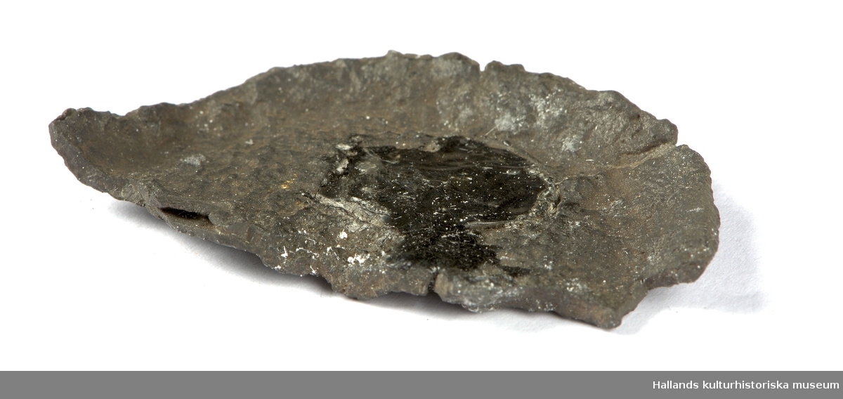 Ett fragment från ett oidentiferat föremål i järn bestående av en halvcirkelformad platta i järn.