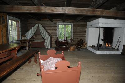 Interiørbilde fra Grimsrudbygningen, her sto langbord med benker, veggfast seng med forheng, vugge og peis i samme rom.
