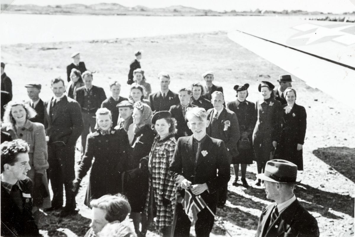 Bodø flyplass 13. mai 1945. En stor folkemengde har møtt opp på flyplassen for å ta imot allierte transportfly.