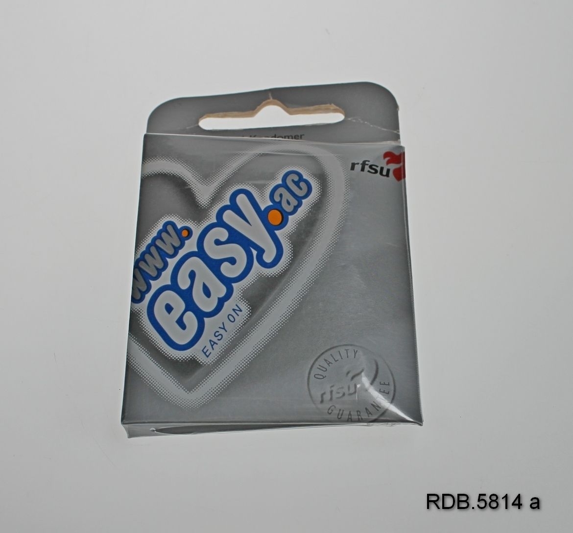 En uåpnet pakke som inneholder 6 kondomer merke Easy. Sølvfarget pappetui. Øverst en utstanset åpning til å henge pakken opp etter.