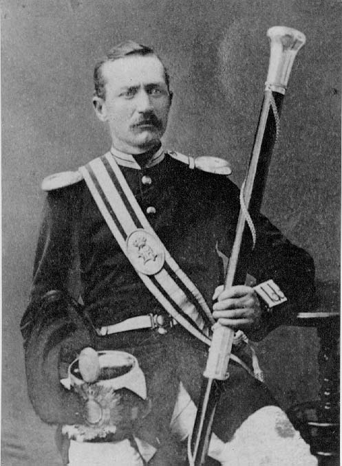 Porträtt av löjtnant August Wilhelm Hall sittande på en stol vid ett bord. Han håller i vänster hand en lång stav med silverknopp och i höger sin kask.