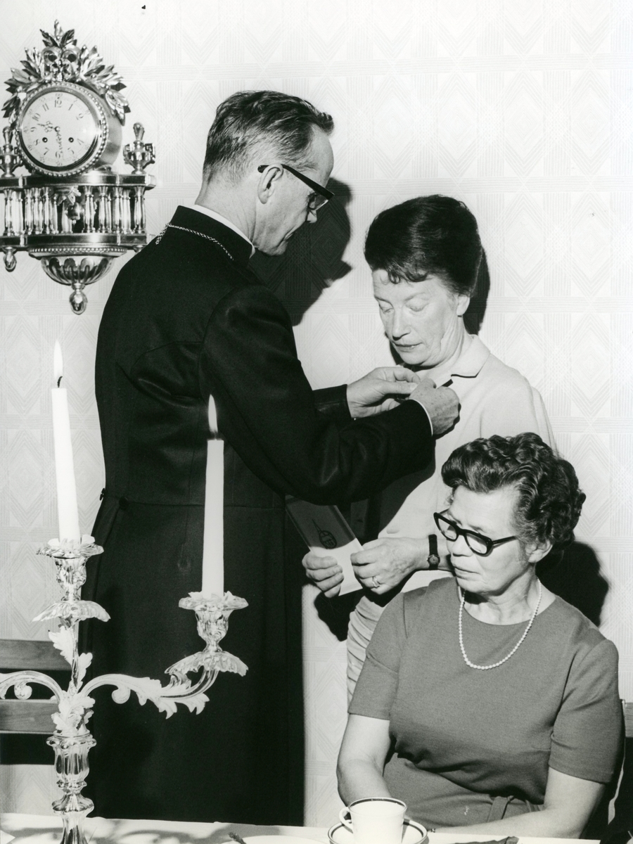 Samkväm i Församlingshemmet vid Biskopsvisitationen år 1966. Medaljutdelning av biskop Bo Giertz till söndagsskollärare Hjördis Magnusson. Sittande är Alma Persson.