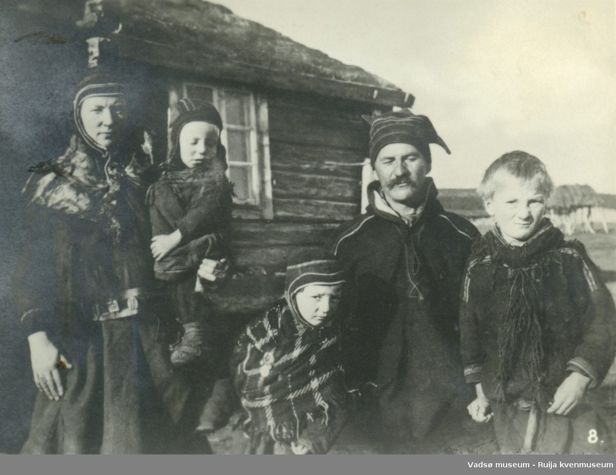 Ukjent samisk familie avbildet foran trehus med torv på taket. Nummerert med nummer 8.