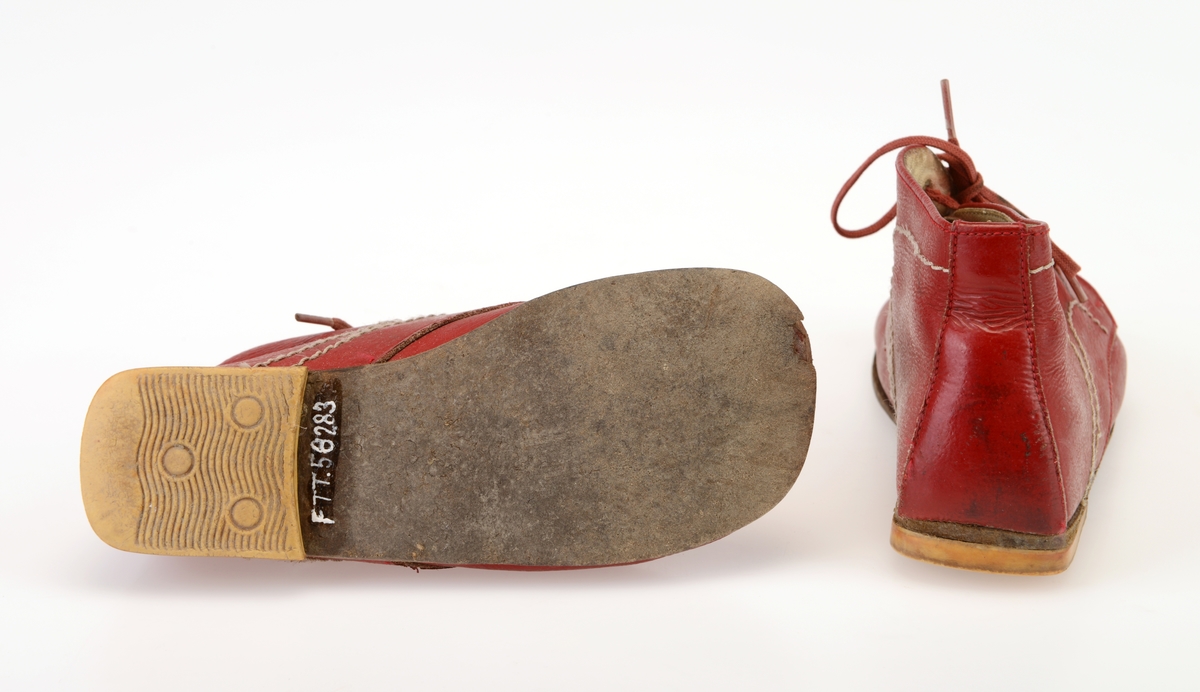 Et par barnesko i størrelse 23. Skoene er i rødt skinn og sydd sammen av to deler. Det er påsydd dekor i form av hvit maskinsøm.Tåen er bred og avrundet. I front er det fire par hull for snøring. Hullene har metallmaljer på baksiden. Skoene er snøret med røde bomullslisser. Under snøringen er det en tunge av rødt skinn som er glatt på utsiden og semsket på innsiden. Skoene er foret med hvitt skinn, også innersålen er av hvitt skinn. Yttersålen er av brunsvart lær, og den er limt på. På hælen er det limt på gule gummisåler.