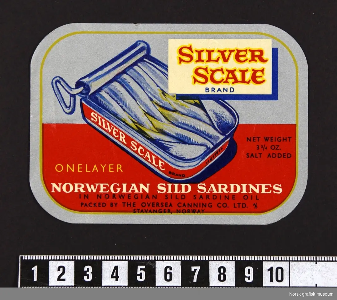 Etikett i rødt og sølv med en illustrasjon av en åpnet hermetikkboks midt på. 

"Norwegian sild sardines in Norwegian sild sardine oil"