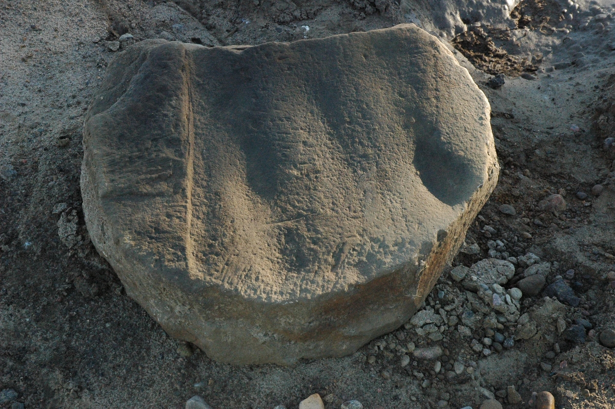 Hörnsten eller möjligen trapphäll till en husrest vid Odensjö gamla bytomt i Barnarps socken i Jönköpings kommun. Byggnadsresten har tolkats som ett kokhus och i huset fanns en rökugn (se även bilderna JMF.00303-1 och -2). Troligen är stenen en återanvänd byggnadsdetalj med dess ursprung är obekant. Bilden har tagits vid en arkeologisk undersökning 2010.