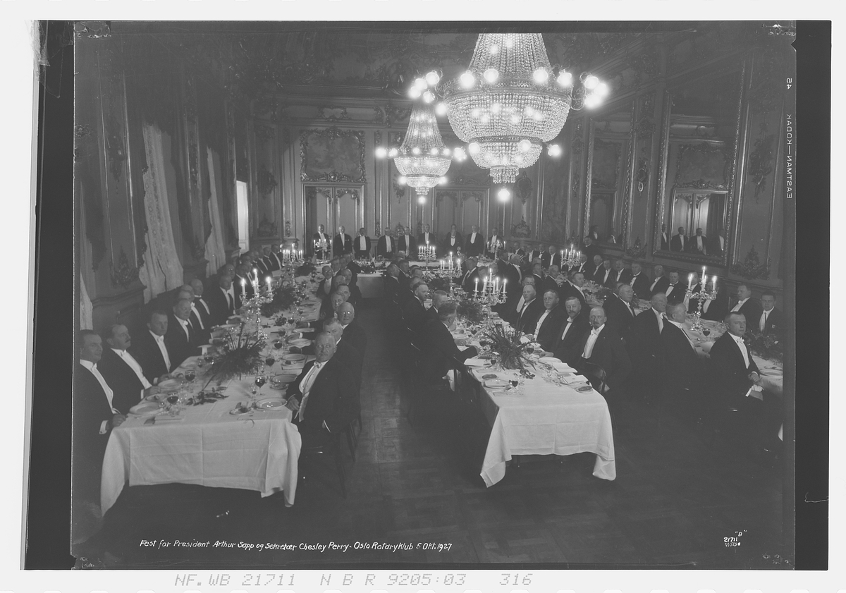 Gruppebilde av Rotary medlemmer rundt et bord. "Fest for Arthur Sapp og sektretær Chesly Perry. Oslo Rotary klubb 5. okt. 1927".