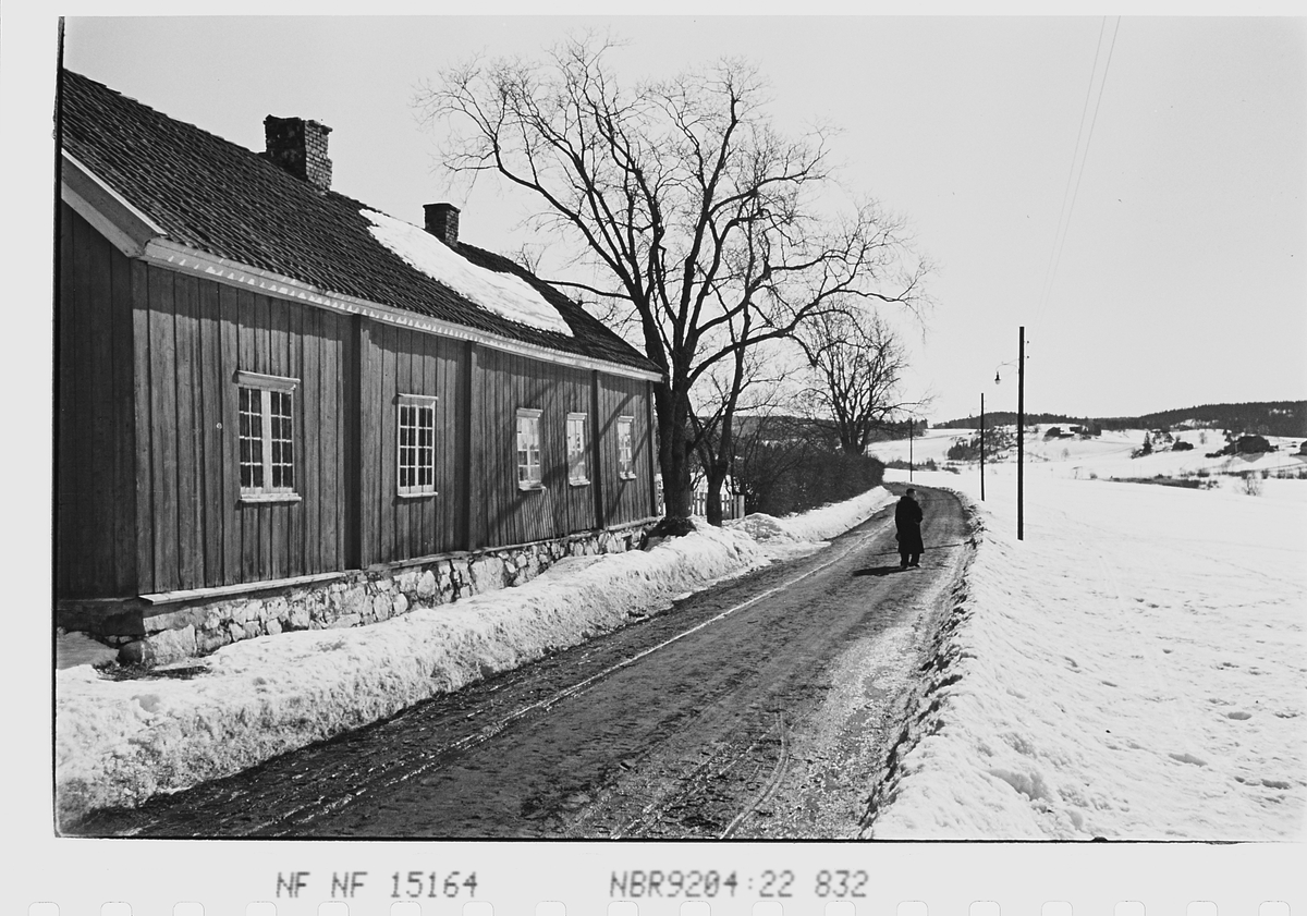 Person ved eldre bygning på vei i vårløsning. Fotografert 1941.