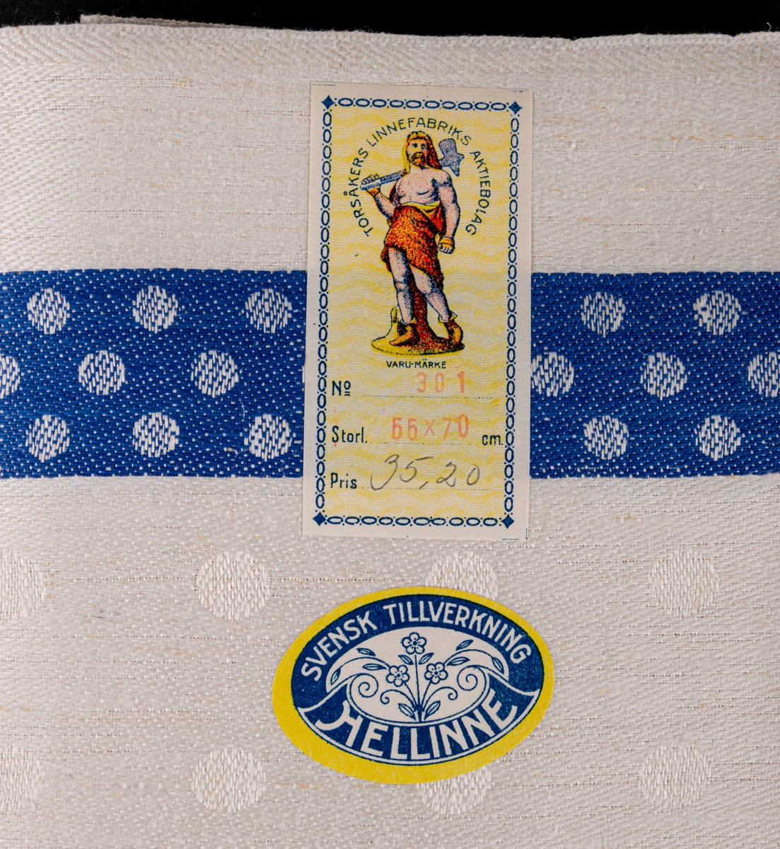 Oklippt, maskinvävd handduksväv av hellinne tillverkad vid Torsåkers linnefabriks aktiebolag. Vävd i tuskaft med naturfärgad botten med blåa effektränder. Försedd med pappersetiketter med tillverkarens emblem.