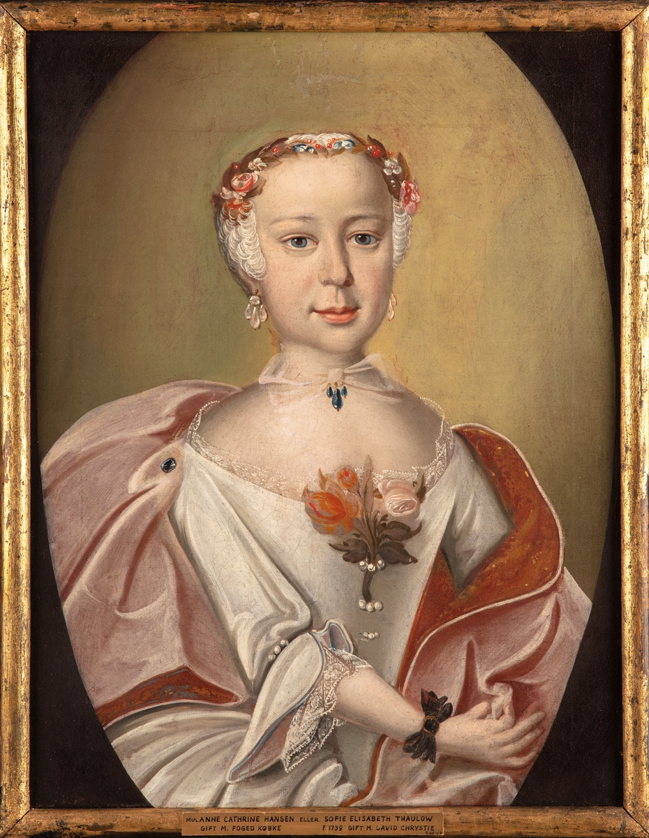 Kvinneportrett, halvfigur, utringet hvit kjole og rosa draperi. Rød blomst i utringning. Pudret hår. Trolig Sophie Elisabeth Thaulow (1739-1779).