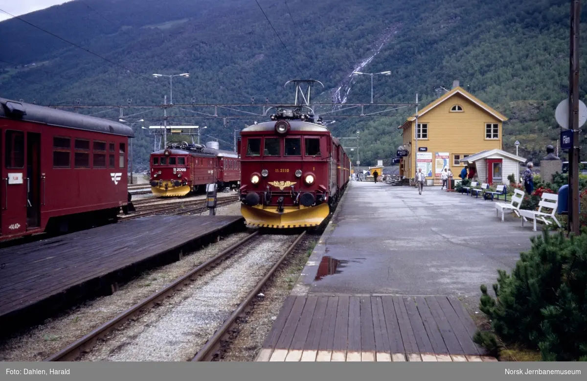 Elektrisk lokomotiv El 11 2110 med persontog til Myrdal på Flåm stasjon. Bak til venstre El 11 2098 og sovevogn litra WLAB