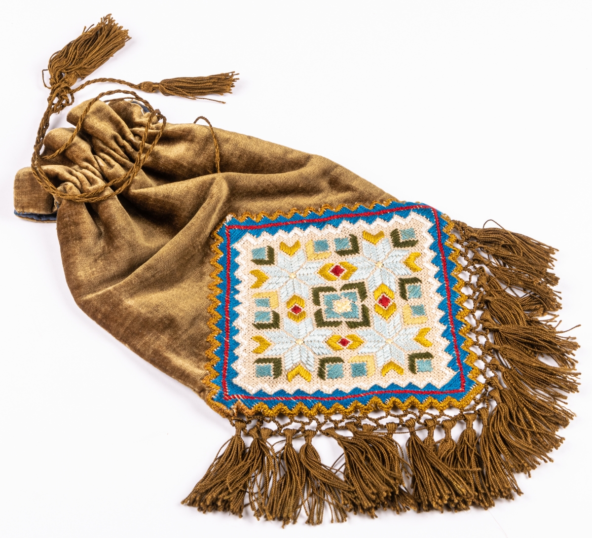 Väska av mossgrönt sammet, påsmodell, frans av bronsfärgat silke och broderi på stramalj.
Från början av 1900-talet.