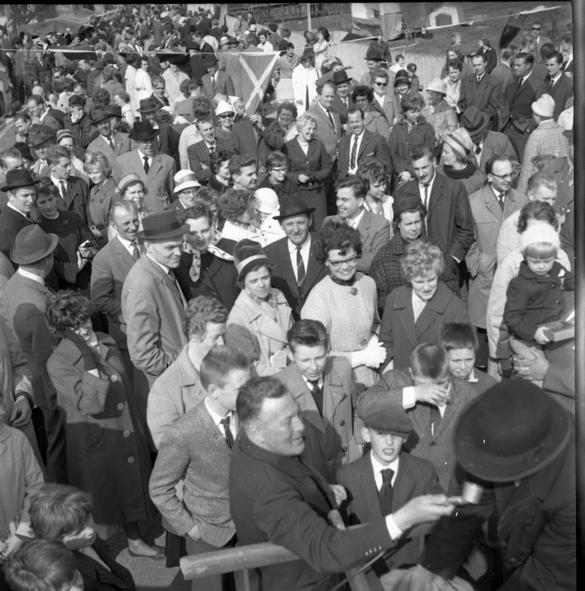 En bild tagen ned mot en stor folksamling på Sjögatan bakom Hallska gården. Till höger i bild syns kubben på en man som intervjuas, av möjligen Herbert Gustafsson.