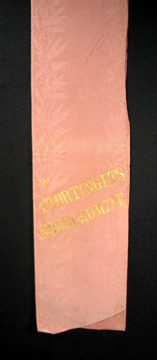 Begravelsessløyfe i rosa silke med tekst i gull.