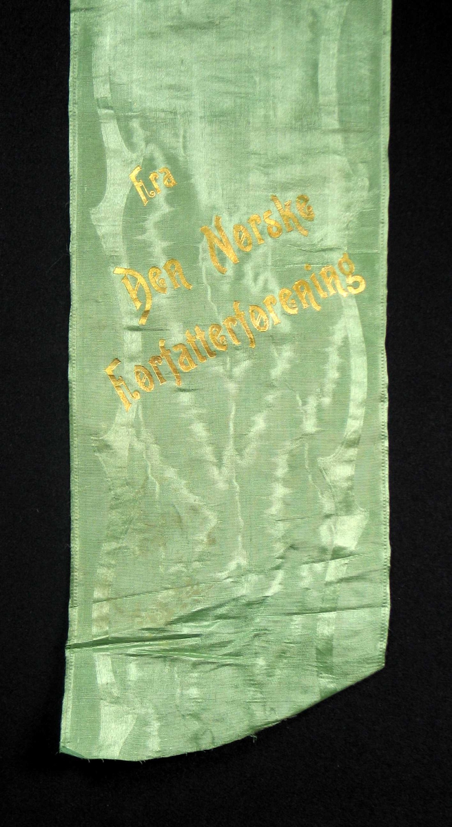 Begravelsessløyfe grønn mønstret silke med tekst i gull.