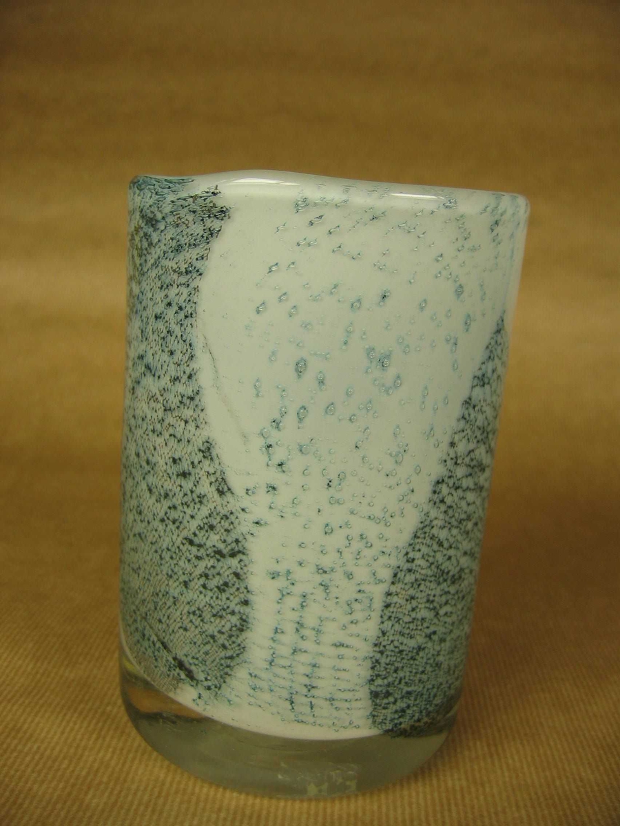 Sylindrisk glassvase av hvitt glass med klart overtrekk. Dekor av blå fiberduk.