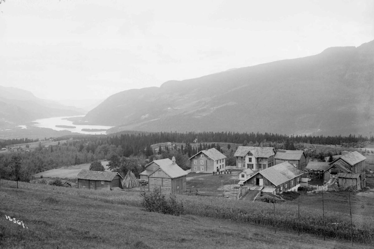 Kort: 30.08.1909. Gården Høystad. To bolighus, mange store og små uthus, dyrket mark, elv, skogkledd åsside.   