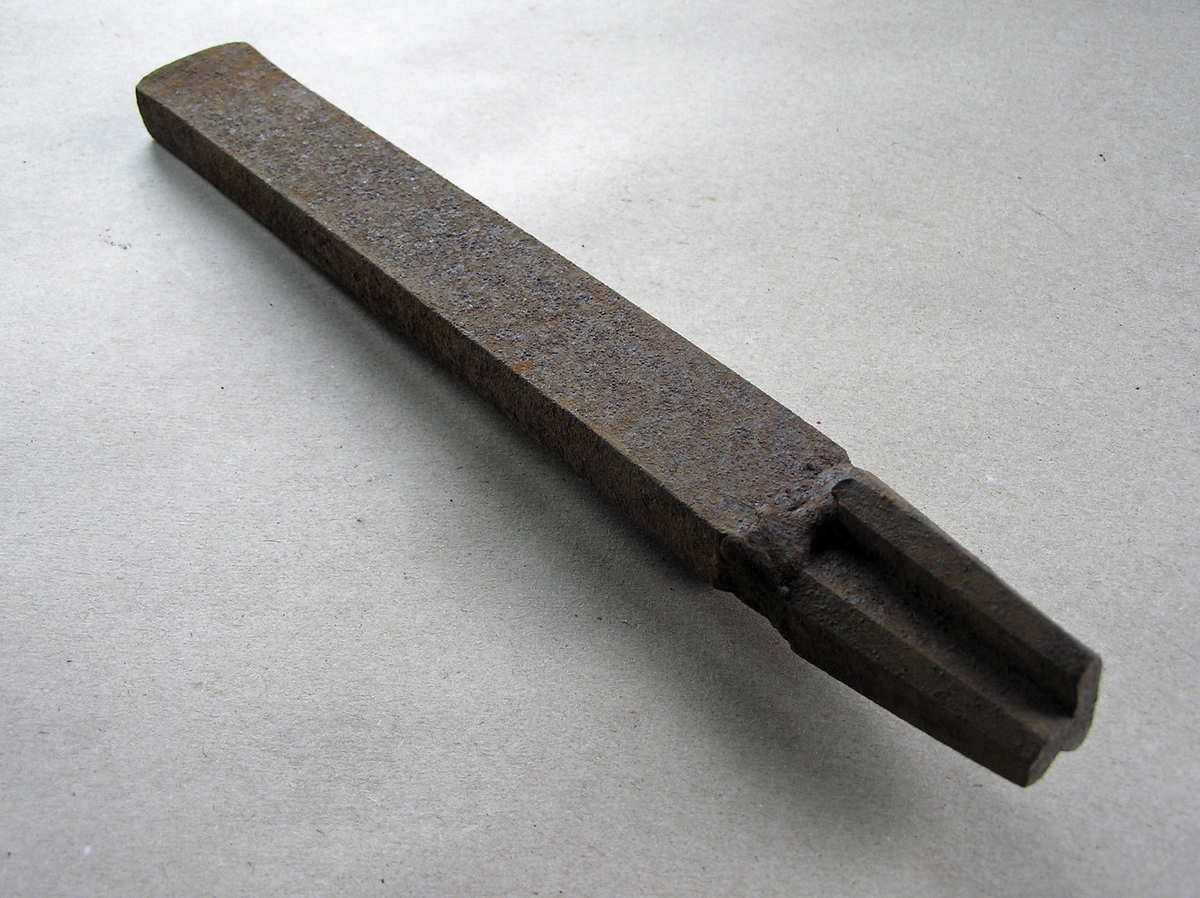 Smidd jernstykke til bruk ved smiing av merkeøks. Merket ble formet rundt stempelet. Tydelig essesveist skjøt mellom stempeldel og håndtak.